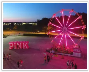 PINK-branded Ferris wheel glowing pink above an evening event