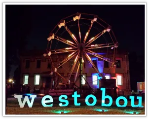 Westobou sign displayed in front of an illuminated Ferris wheel at night