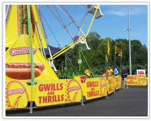 Gwaltney-branded Ferris wheel entrance with yellow GWILLS AND THRILLS fencing